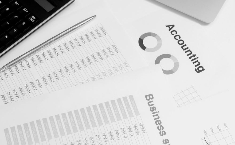 桌上的笔记本电脑、计算器与财务文件 · Laptop, calculator and financial documents on a desk